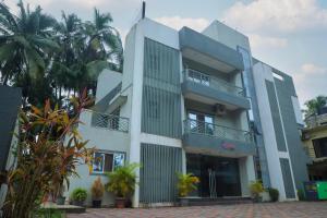 a white building with palm trees in front of it at Encasa Resort in Nagaon