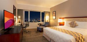 a hotel room with a bed and a flat screen tv at Equatorial Ho Chi Minh City in Ho Chi Minh City