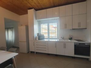 a kitchen with white cabinets and a sink and a window at Piazza di Lefkimmi in Lefkimmi +13 photos