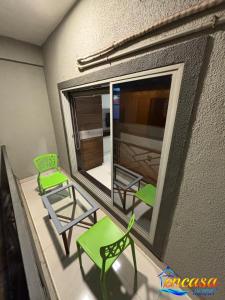 a balcony with two green chairs and a mirror at Encasa Resort in Nagaon