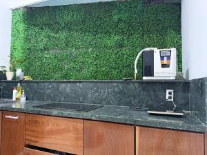 a kitchen with a counter with a green wall at KEYDEO House in Phan Thiet