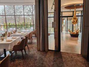 a restaurant with white tables and chairs and windows at Rosslyn Dimyat Hotel Varna in Varna City