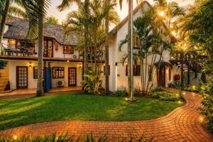 a house with palm trees and a brick driveway at The Villa Manor & Spa Exclusive Escape in Bela-Bela