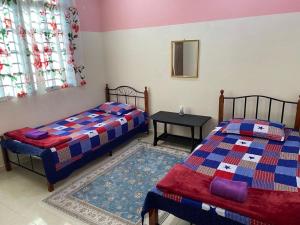 a bedroom with two beds and a table in it at Homestay 3U MU5L1M Only in Cukai