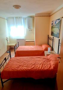 a bedroom with two beds and a table and a window at B&B Nuova Loggia in Fabriano