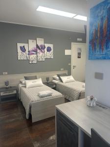a room with two beds and paintings on the wall at B&B Caricone in Orta Nova