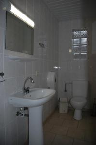 a white bathroom with a sink and a toilet at Le Domaine Appartements in Bilstain