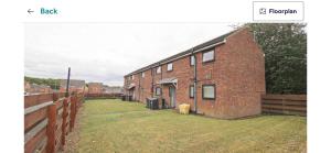 a brick building with a grass yard next to a fence at Beamish apartment in Pelton