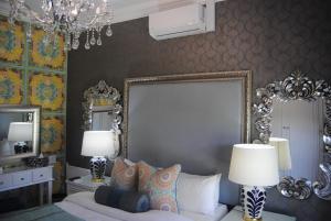 a bedroom with a bed with two lamps and a mirror at Villa Grande Luxury accommodation in Welkom