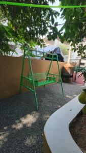 a green swing sitting under a tree next to a sidewalk at Dreamers Lounge in Trichūr