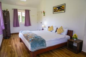 a bedroom with a large bed with purple curtains at Winterbourne Chalet in Coonoor