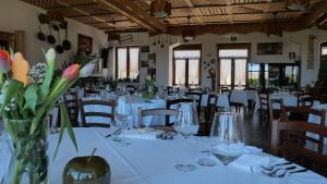 a dining room with white tables and chairs and flowers at Hotel Casa Vacanze Orchidea in Pinerolo