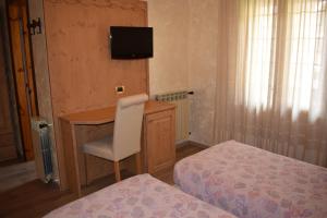 - une chambre avec un bureau, une chaise et un lit dans l'établissement Hotel Mignon, à Ponte di Legno