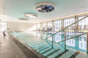 a large swimming pool in a building with windows at Solny Resort Apartament A245 in Kołobrzeg