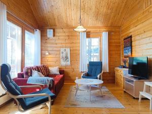 a living room with a red couch and two chairs at Kulkuri in Syöte