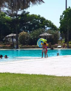 a man holding an umbrella next to a swimming pool at Maison à Cabonegro in Cabo Negro