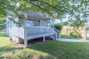 a white house with a porch with a white railing at Crossroads Cottage l Grill & high speed internet in Chattanooga