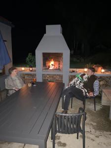 a couple of people sitting at a picnic table with a fireplace at Stoneygate Farm in Wakkerstroom