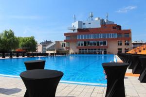 a large swimming pool with black chairs in front of a building at Apartman CITY CENTER 9 BAZEN in Prijedor