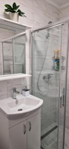 a white bathroom with a sink and a shower at Opal Skay Apartment in Doboj