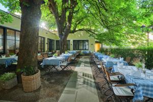 a restaurant with white tables and chairs under trees at Hotel Sailer in Innsbruck