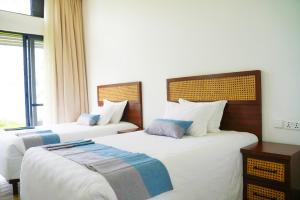 a bedroom with two beds and a window at Eben Lake Kivu cottages and Villas in Kagano