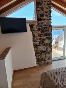 a living room with a stone wall and a flat screen tv at Casa Carlotta in Perledo