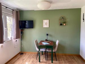 a dining room table with chairs and a television on a wall at Tiny House Zur Alten Sparkasse in Groß Garz