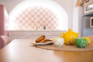 a table with a yellow tea pot and two cups at Pantabrì - Casa Tipica su Mare nel Centro Storico di Gallipoli in Gallipoli