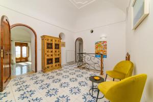 a living room with yellow chairs and a tiled floor at Estate4home - Casa Bouganville in Positano +26 photos