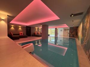 a large swimming pool in a house with pink lighting at Hotel Am Triller - Hotel & Serviced Apartments - Pool & Relax Lounge in Saarbrücken