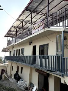 a building with a balcony with a sign on it at Rautela Homestay in Lansdowne