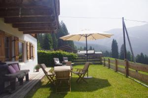 a patio with a table and chairs and an umbrella at READYNOW Alpine Resonanz Camp für mentale Klarheit in Pill