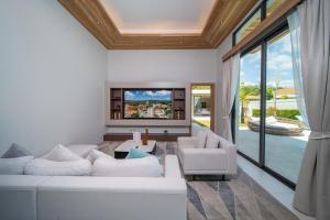 a living room with a white couch and a tv at Mouana Breeze Mai Khao VIP 4-bedroom Pool Villa 9911 in Phuket