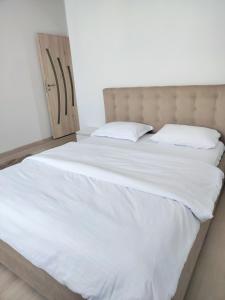 a large bed with white sheets and a wooden door at Sibiu Edge Retreat in Sibiu