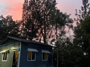 a blue house with trees in the background at Resort Rover - Sampala in Masinagudi