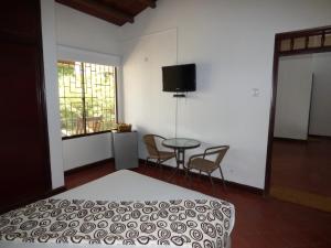 a bedroom with a bed and a table and a window at Hostal Mizare Valledupar in Valledupar