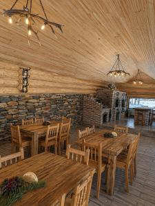 a restaurant with wooden tables and chairs and a stone wall at Casa Pădurarului in Câmpulung Moldovenesc