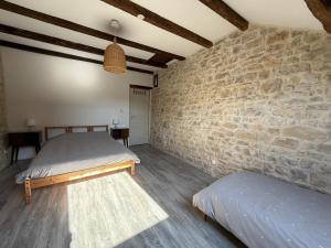 a bedroom with two beds and a stone wall at L'Epicerie in Melay +26 photos