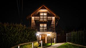 a wooden house at night with lights on it at Jaworowa Osada in Brenna