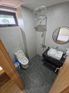 a bathroom with a toilet and a sink and a mirror at Huỳnh Nga Măng Đen Hotel in Kon Plong