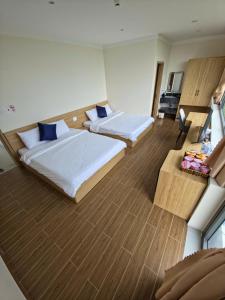 a hotel room with two beds and a desk at Huỳnh Nga Măng Đen Hotel in Kon Plong
