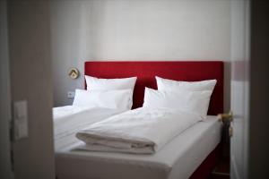 two beds with white sheets and a red headboard at Ferienwohnung "Haus Lehlgässchen" in Reil