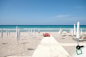 a red car on a sandy beach with umbrellas at Hotiday Gallipoli Spiaggia in Baia Verde