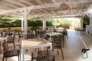 a patio with tables and chairs under a pergola at Hotiday Gallipoli Spiaggia in Baia Verde