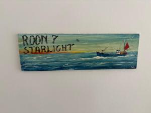 a painting of a boat in the ocean on a wall at Cadgwith Cove Inn in Cadgwith +66 photos