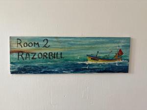 a painting of a boat in the water on a wall at Cadgwith Cove Inn in Cadgwith
