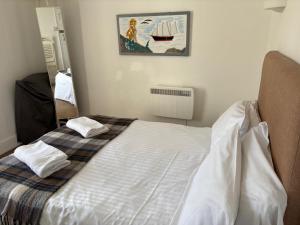 a white bed in a room with a picture on the wall at Cadgwith Cove Inn in Cadgwith