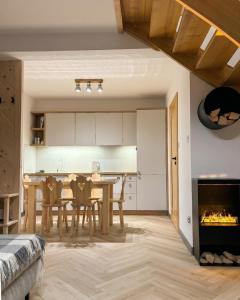 a kitchen and dining room with a table and a fireplace at Domki Tomanova - Premium Chalets in Dzianisz +43 photos