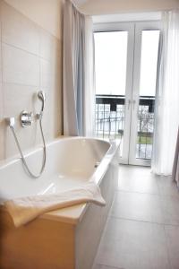 a white bath tub in a bathroom with a window at Hafenhotel Meereszeiten in Heiligenhafen +26 photos